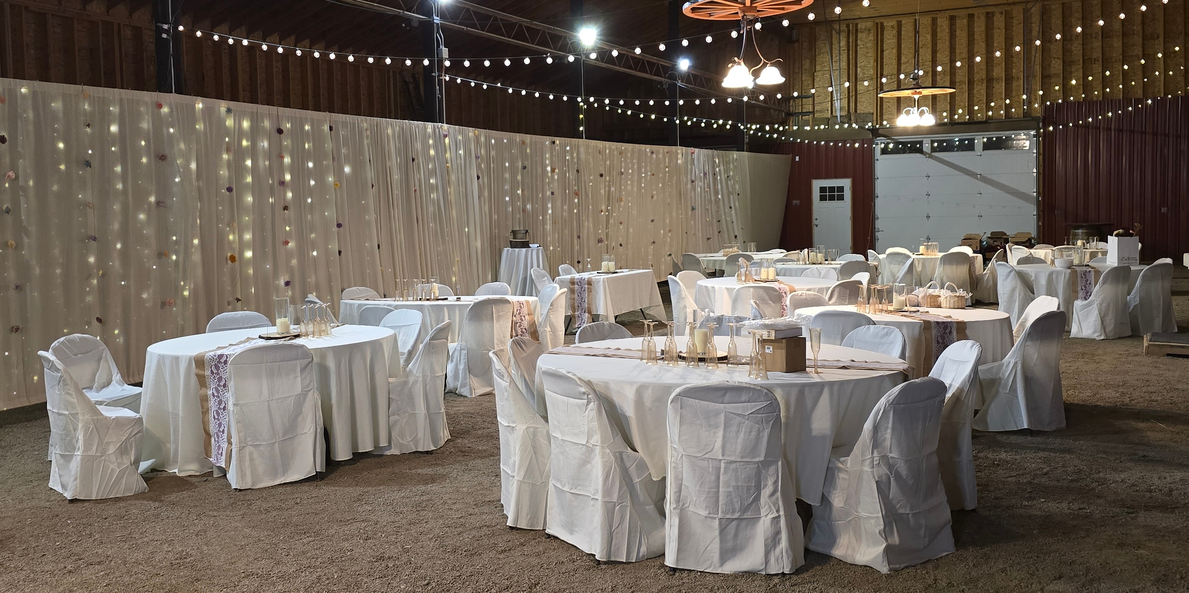 Barn reception setup with string lights and white linens