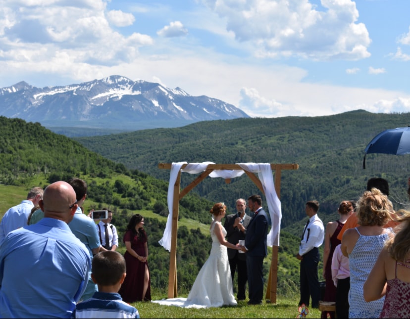 Wedding ceremony at the wooden arch with panoramic mountain views and guests gathered