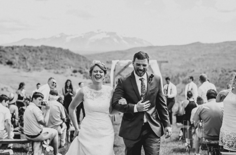Black and white photo of bride and groom laughing as they walk the recessional